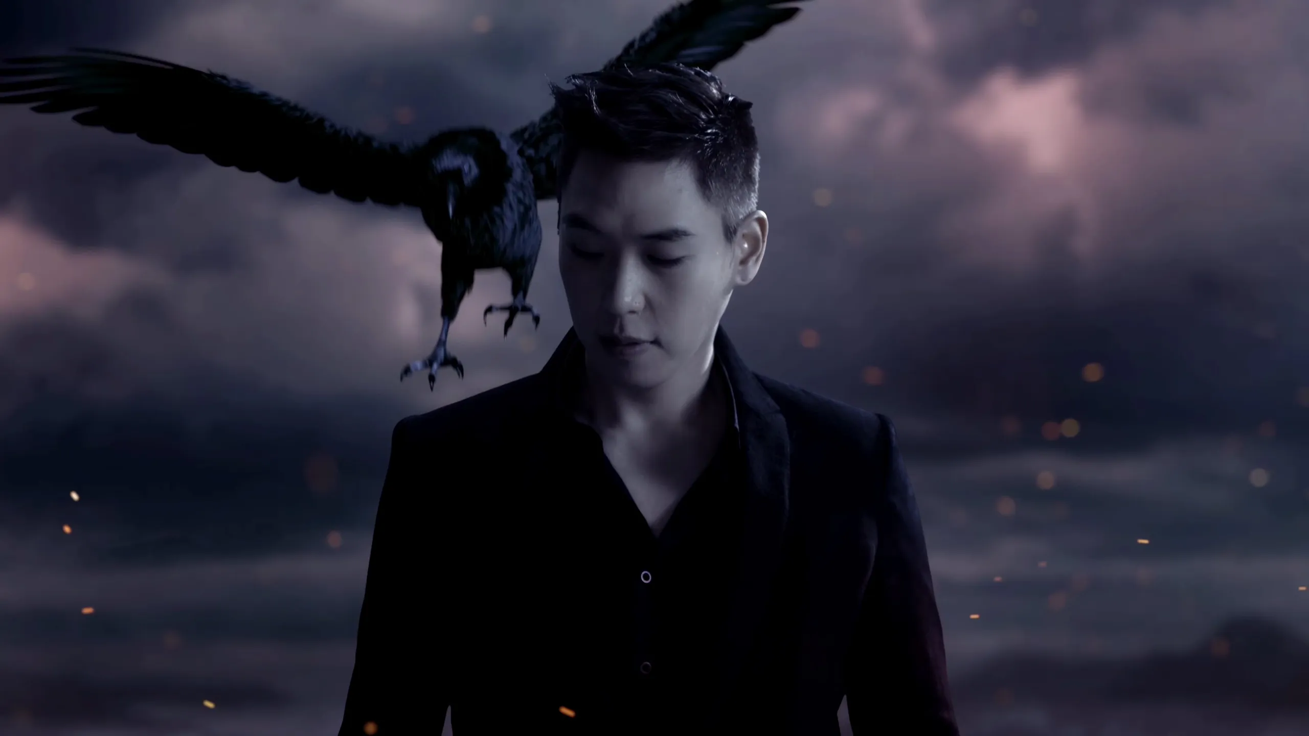 CG raven with wings spread landing beside the head of a live-action man in a dark suit, against a stormy, ember-lit night sky