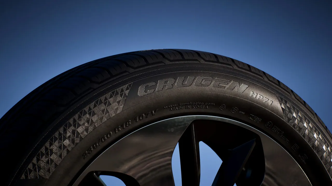 Extreme CG close-up of a tyre sidewall and tread against a deep blue sky, with moulded product lettering and size markings legible