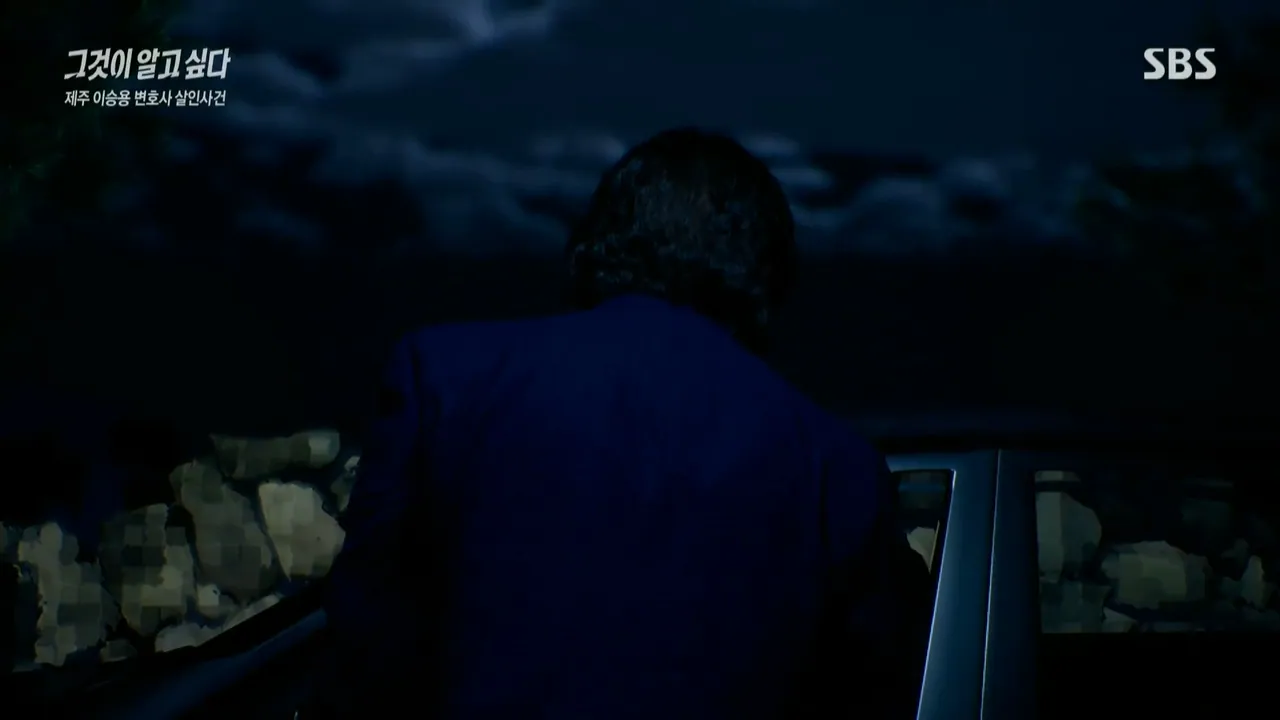 Night reconstruction frame of a figure in a blue jacket leaning over a car door, with parts of the frame obscured for broadcast